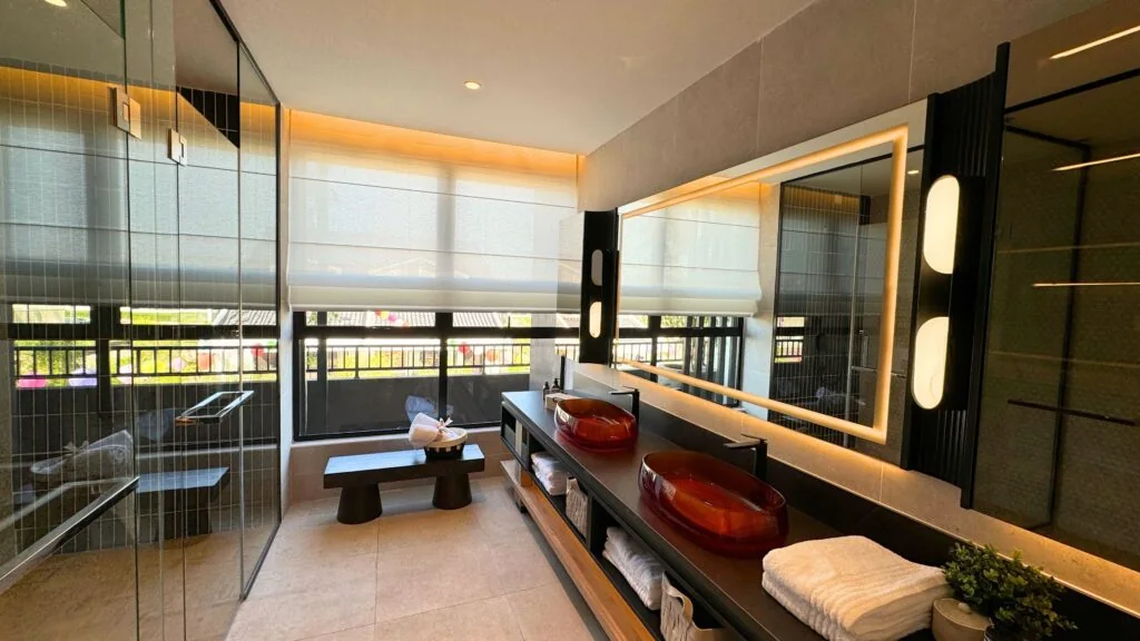Master bathroom at Bungalow Dees with twin vessel basins, backlit mirror and a glass shower
