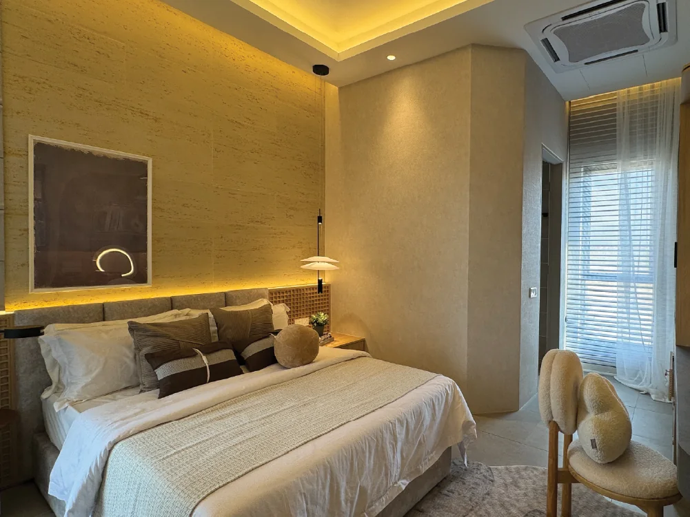 Master bedroom at Bungalow Dees with travertine feature wall, cove lighting and a balcony beyond